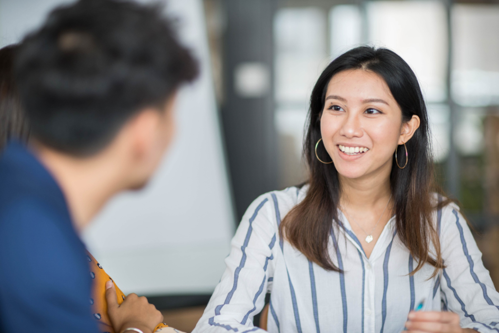 Smiling woman having a conversation with a colleague in an office setting.
