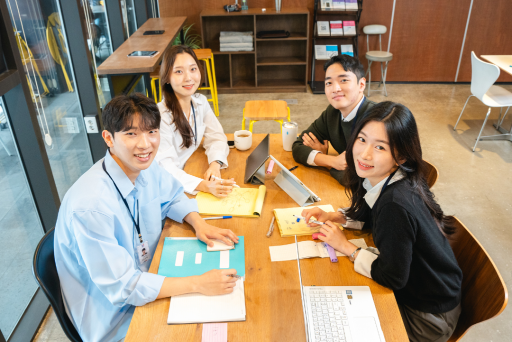 กลุ่มเพื่อนร่วมงานสี่คนกำลังประชุมอย่างเป็นกันเองและระดมความคิดบนโต๊ะทำงานในออฟฟิศ